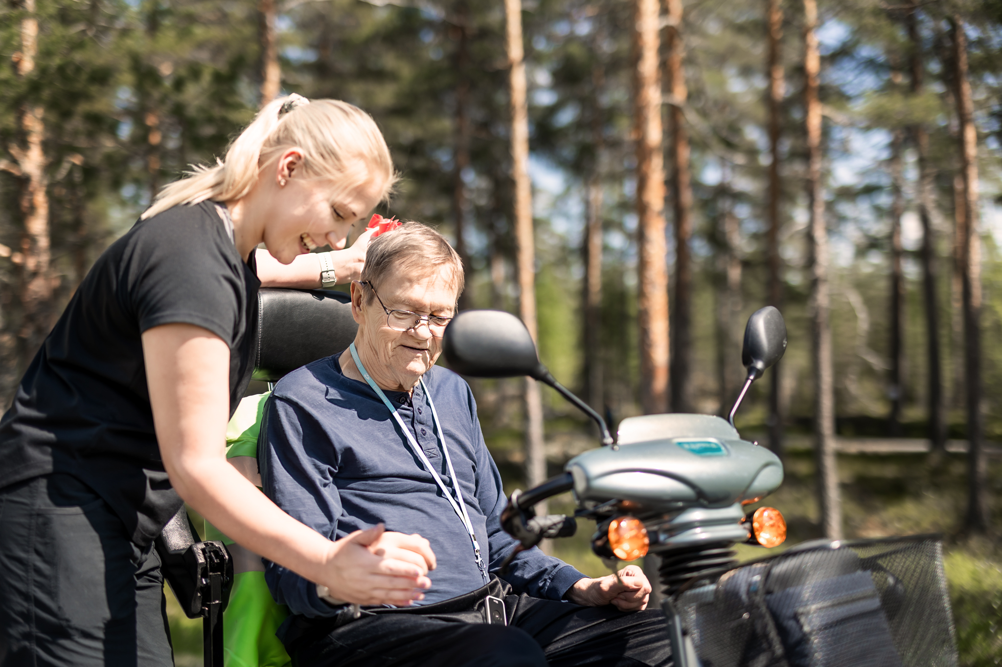 Fysioterapeutti pitää asukasta kädestä. Taustalla Kunnonkodon oma kangasmetsä.